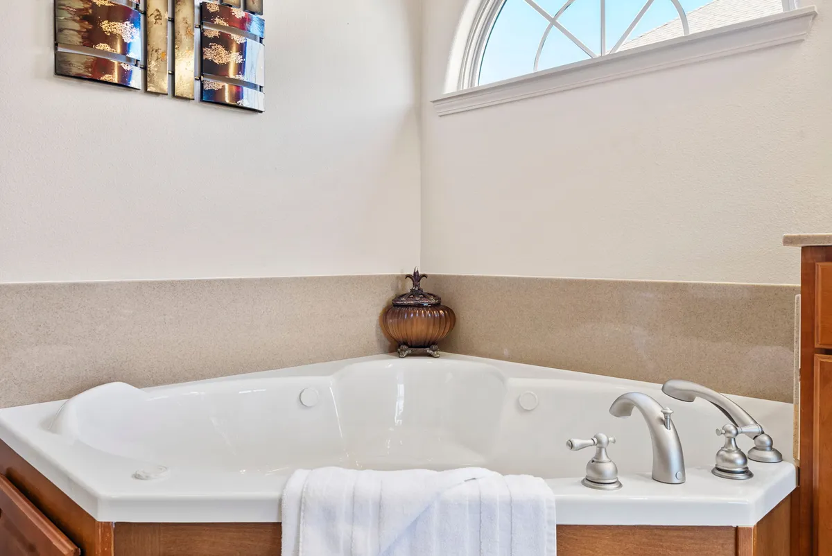 A tranquil bathroom scene featuring a jacuzzi tub, decorative wall art, and a window letting in soft natural light. The space invites guests to indulge in self-care and relaxation after a busy day.