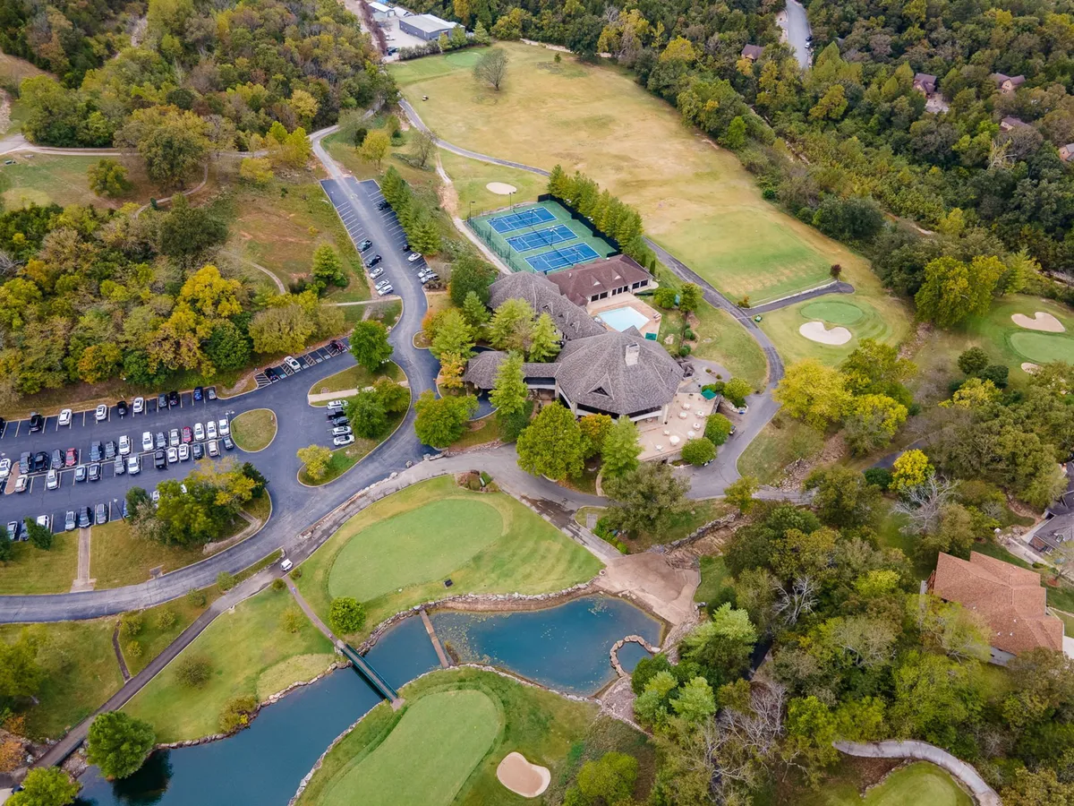 A vibrant aerial view showing the resort’s golf course, sparkling swimming pool, tennis courts, and clubhouse, all surrounded by lush greenery. The image captures a snapshot of the community’s recreational amenities, showcasing spaces for swimming, tennis, golf, and social gatherings outdoors.