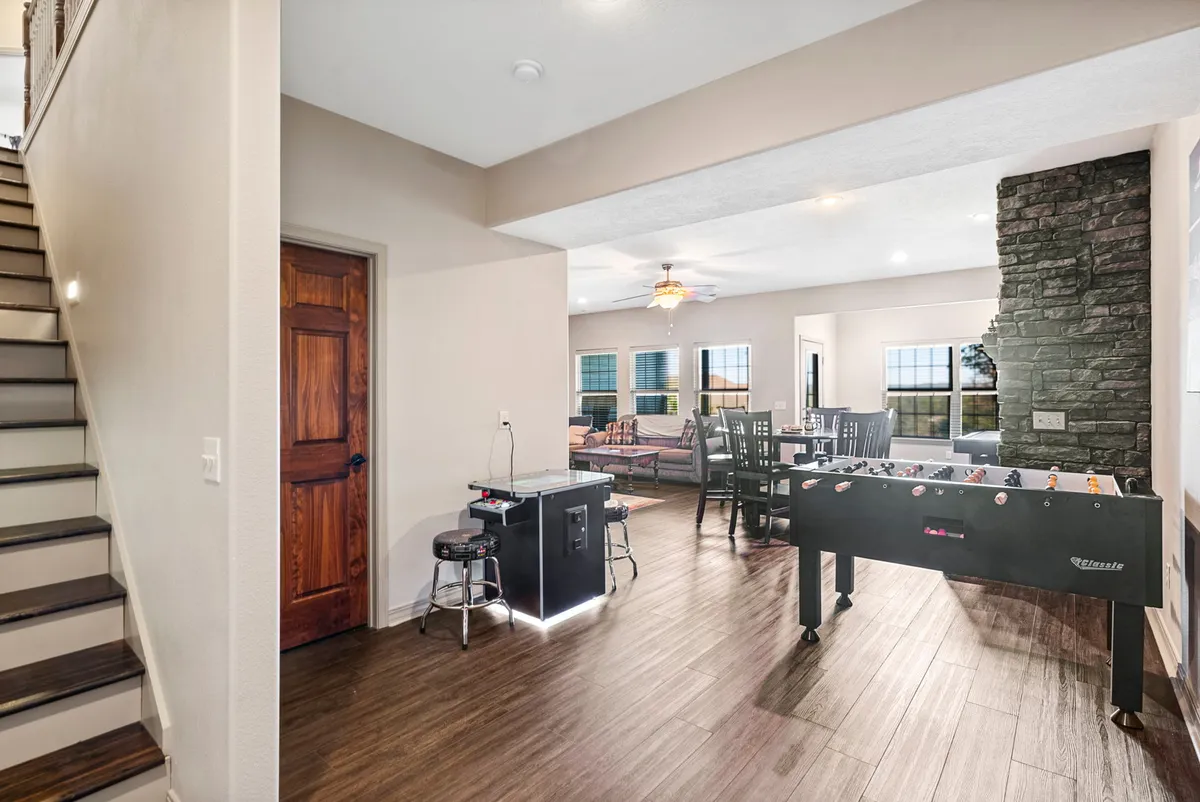 A foosball table is the central focus of this image, positioned in a bright, lively space that also includes a casual dining area and comfortable sofa seating. The room feels open and social, ideal for group activities ranging from games to shared meals.